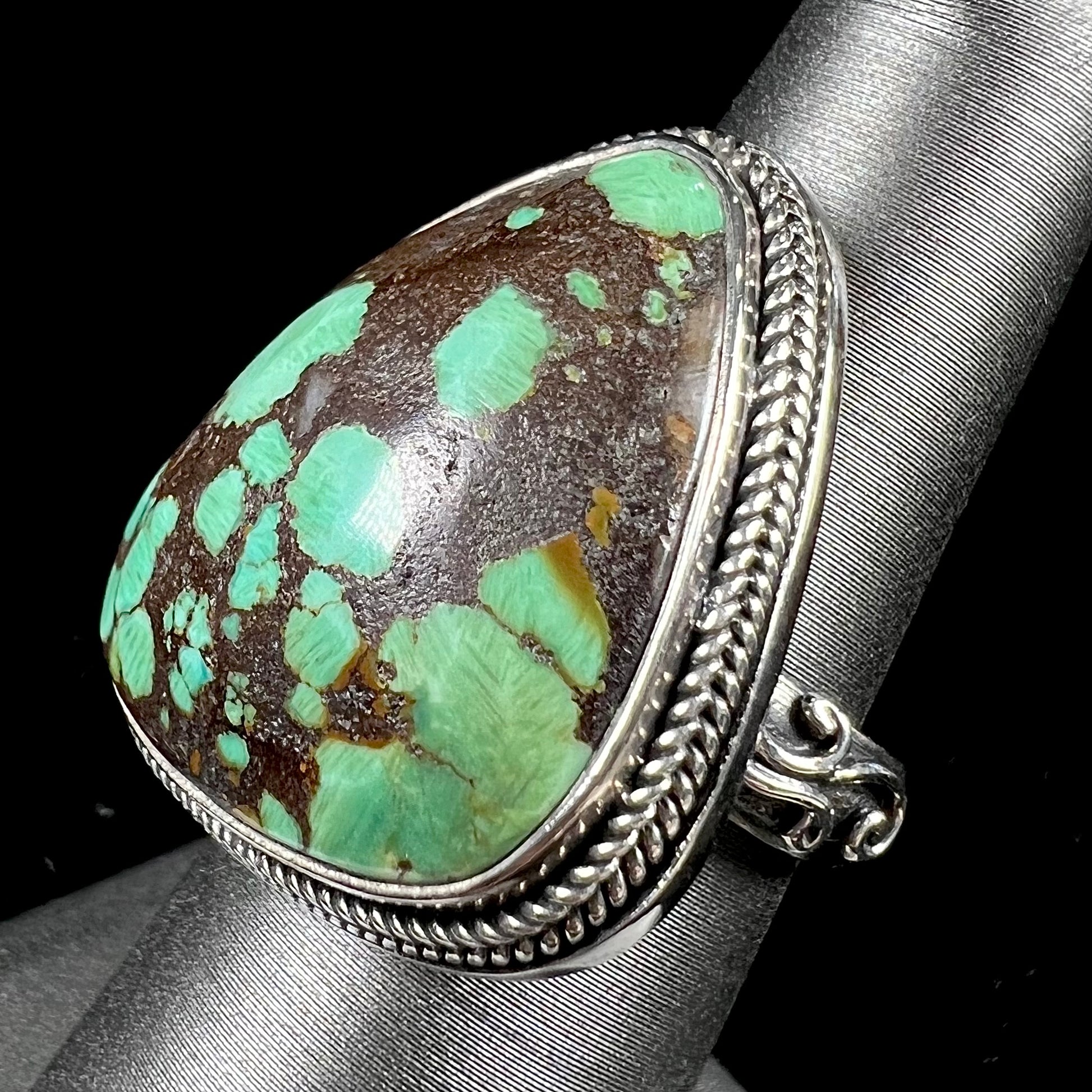 A sterling silver ring bezel set with a green spotted turquoise stone from Carico Lake, Nevada.
