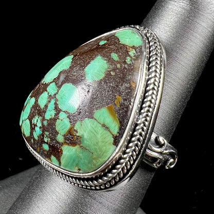 A sterling silver ring bezel set with a green spotted turquoise stone from Carico Lake, Nevada.