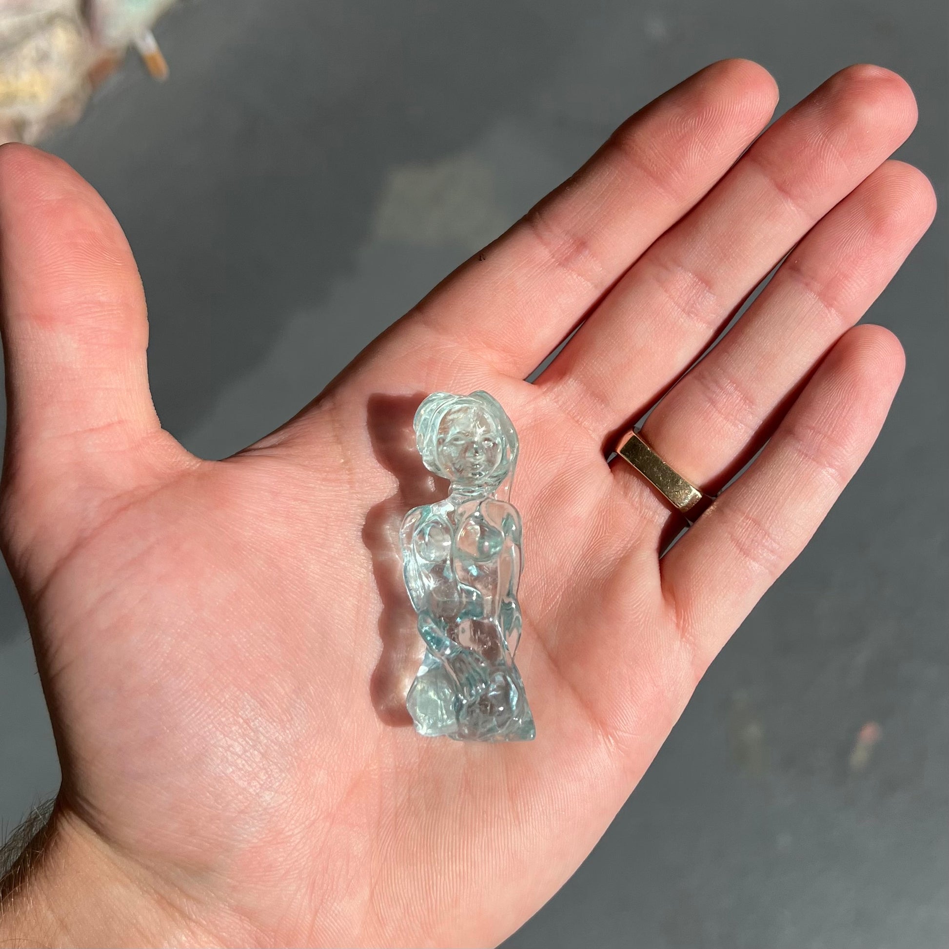 A stone woman figure carved from a blue aquamarine crystal.  The piece resembles Venus Gummi de Milo.