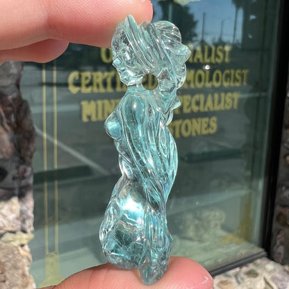 A stone woman figure carved from a blue aquamarine crystal.  The piece resembles Venus Gummi de Milo.
