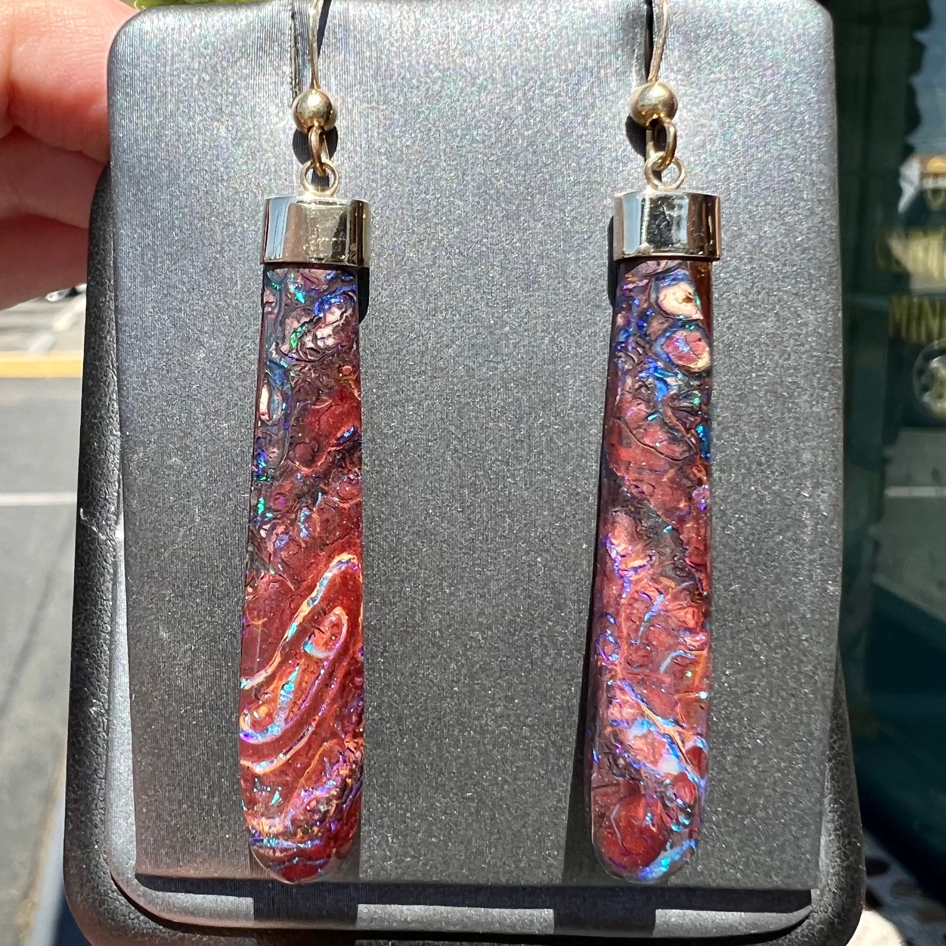 A pair of yellow gold cap Koroit boulder opal dangle earrings.  Purple highlights are seen.