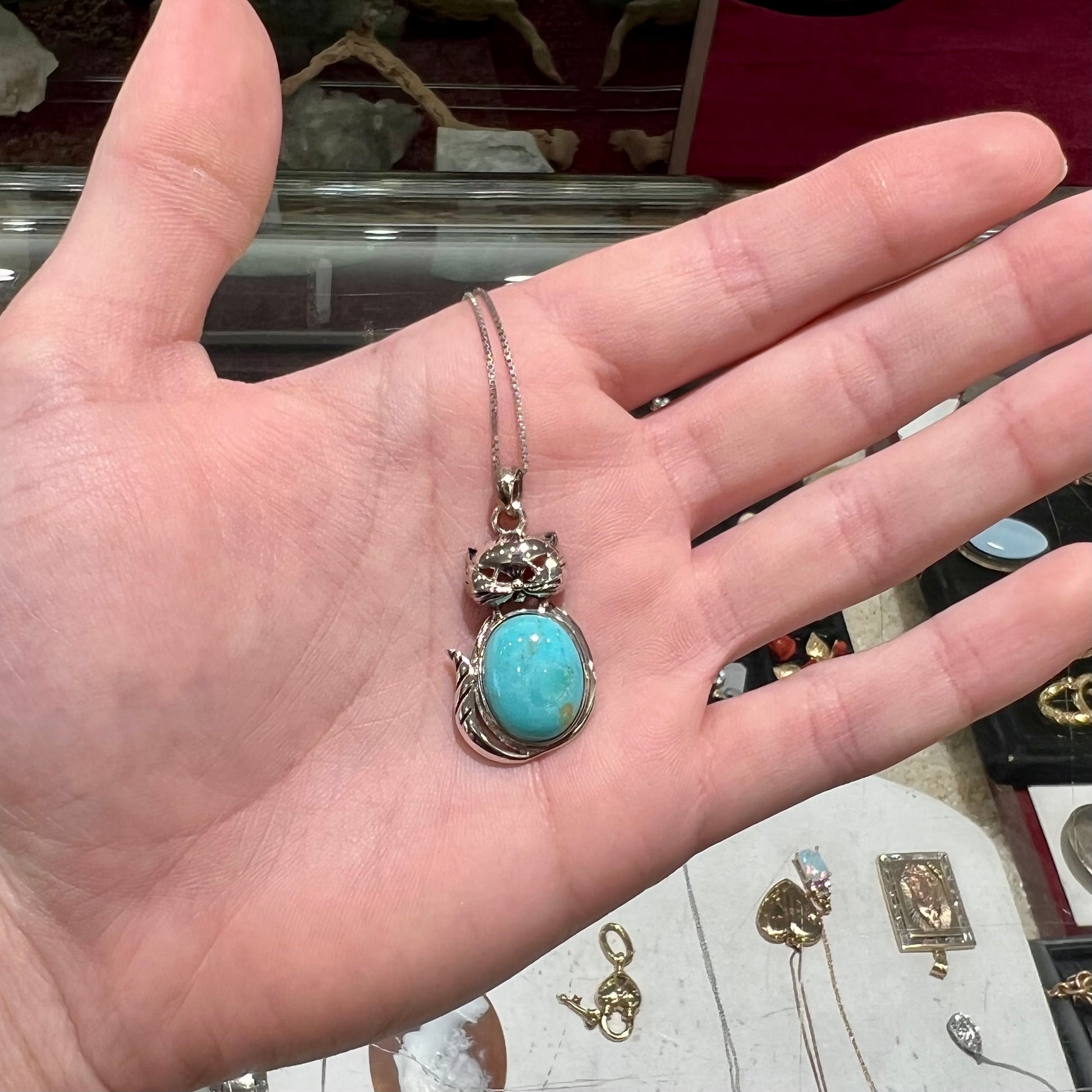 A sterling silver cat necklace set with an oval cut Sleeping Beauty turquoise stone.