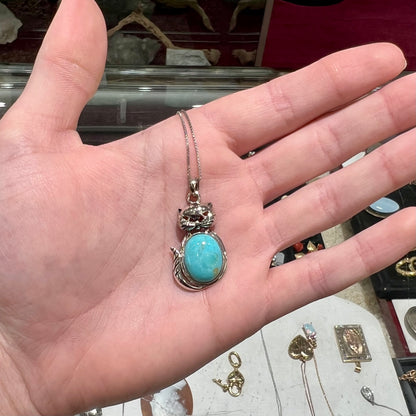 A sterling silver cat necklace set with an oval cut Sleeping Beauty turquoise stone.