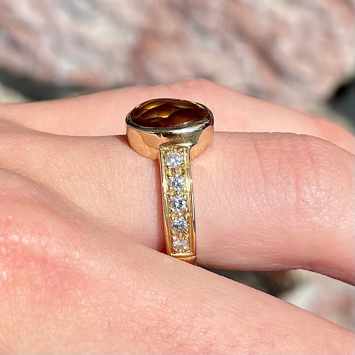 A ladies' oval cabochon cut fire agate and diamond engagement ring cast in yellow gold.