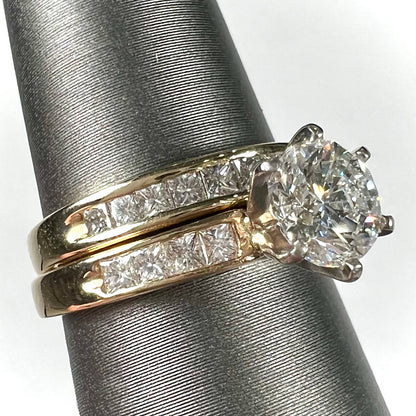 A diamond engagement and wedding ring set.  The center stone is a 1 carat round diamond, and the side stones are channel set princess cut diamonds.