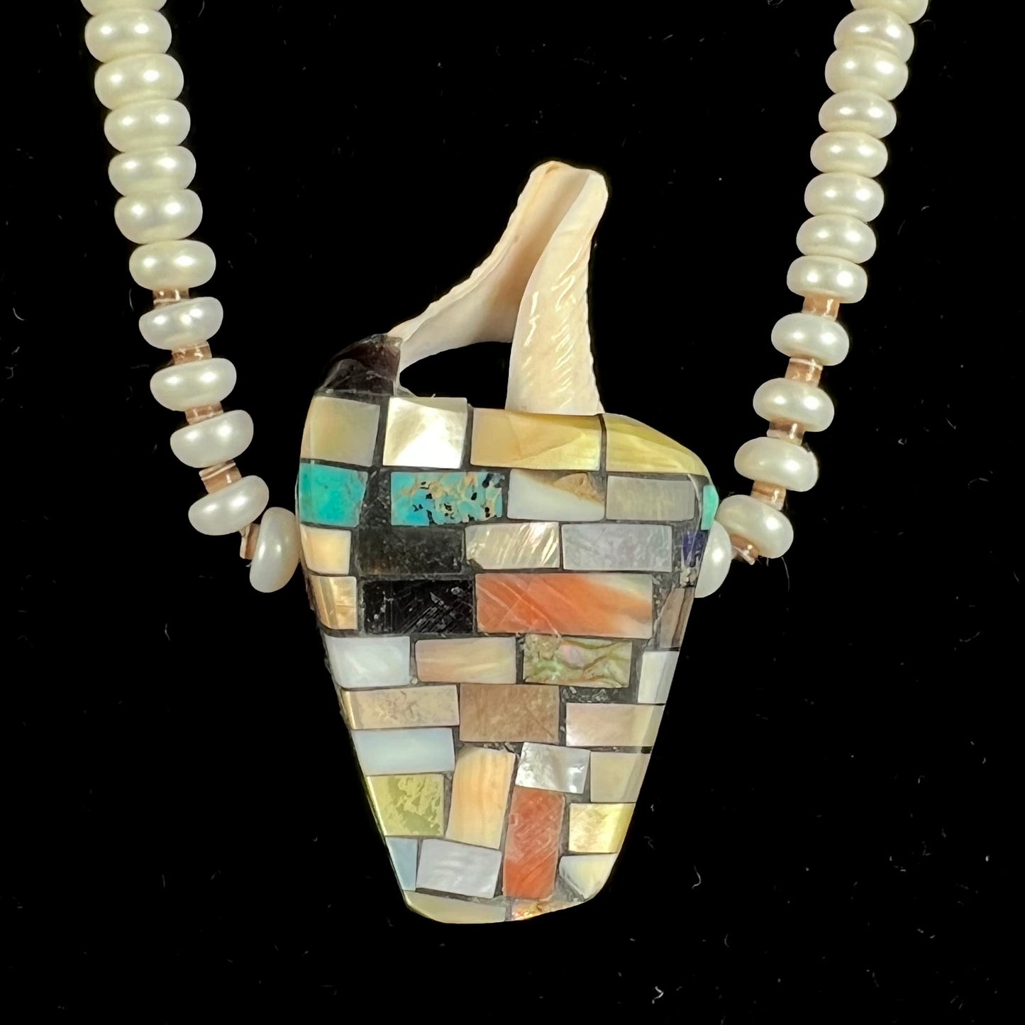 A seashell necklace that has been inlaid with spiny oyster and mother of pearl shell on a pearl bead necklace by Charlene Reano.