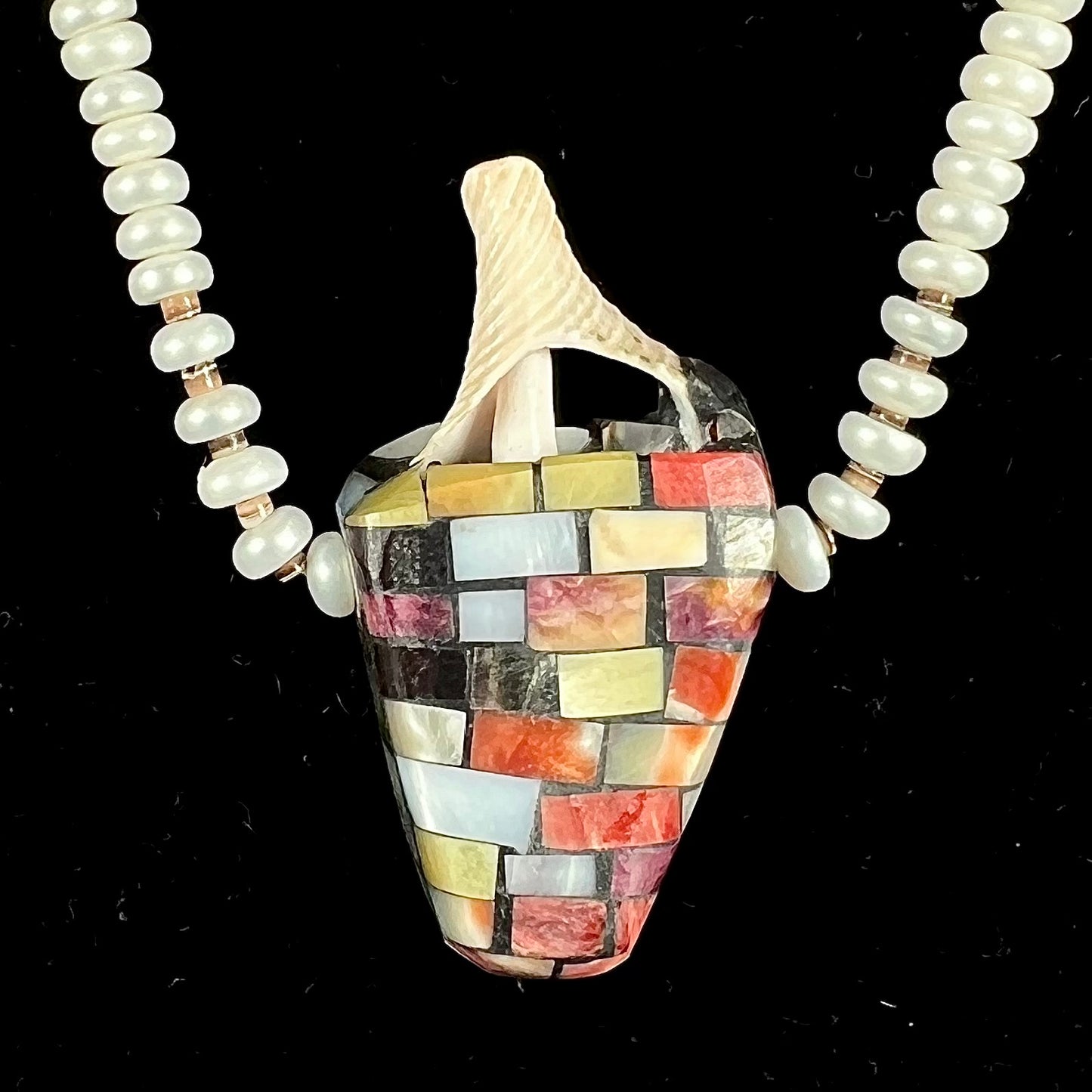 A seashell necklace that has been inlaid with spiny oyster and mother of pearl shell on a pearl bead necklace by Charlene Reano.