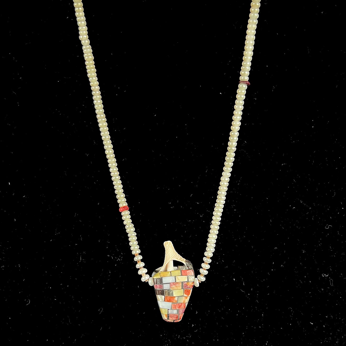 A seashell necklace that has been inlaid with spiny oyster and mother of pearl shell on a pearl bead necklace by Charlene Reano.