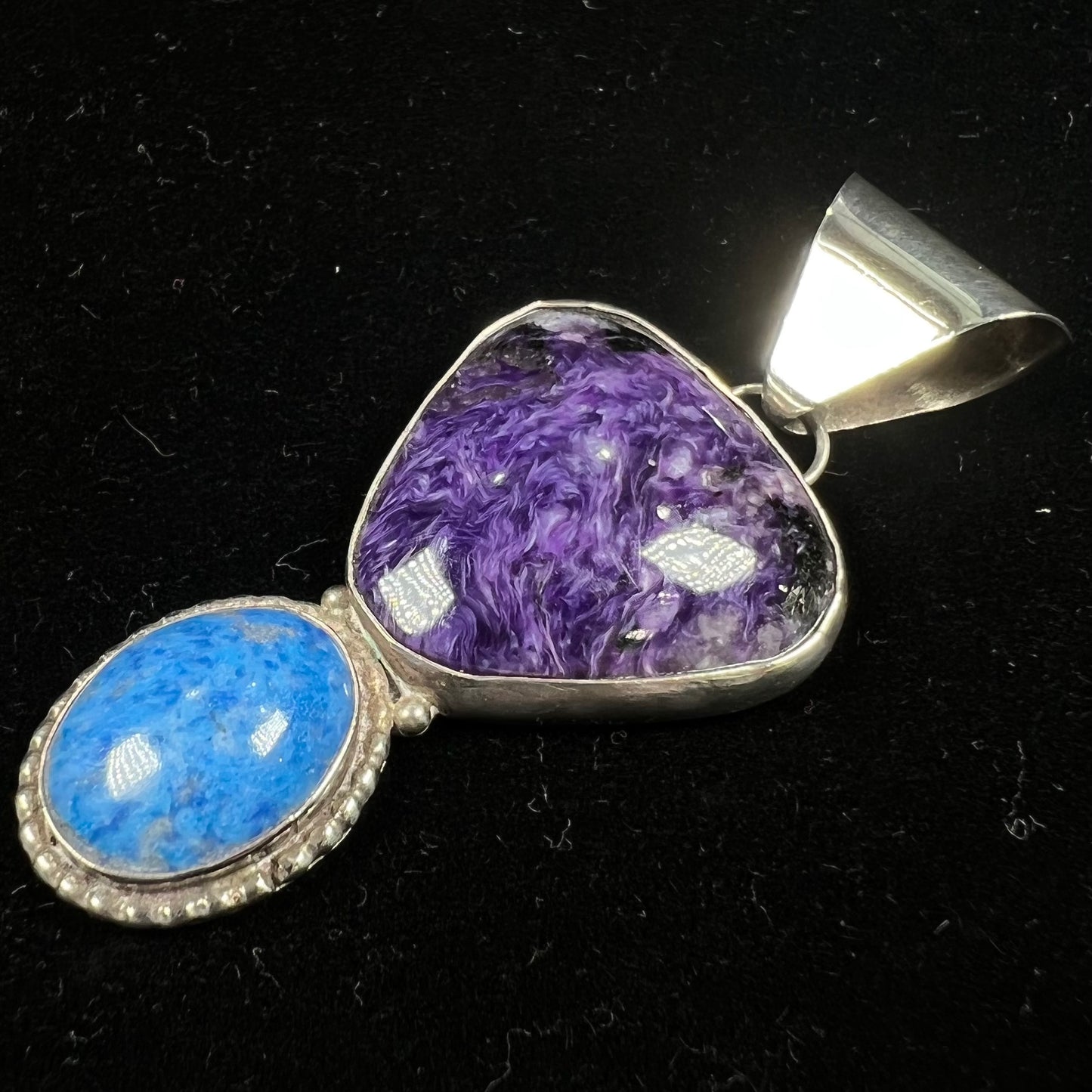 A sterling silver pendant set with polished charoite and lapis lazuli stones, hand signed "KK" by the artist.
