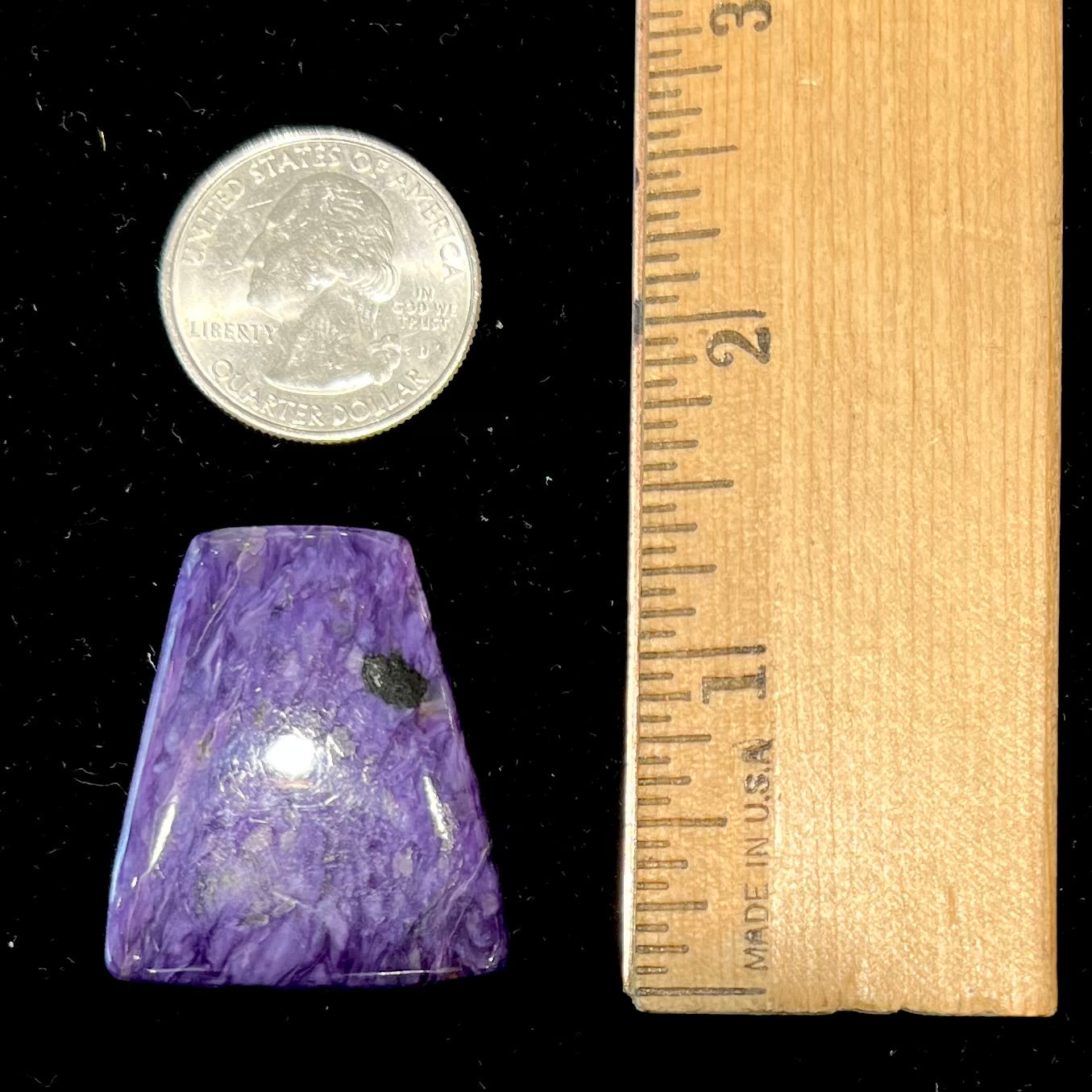A loose, trapezoid cabochon cut purple charoite stone from Russia.