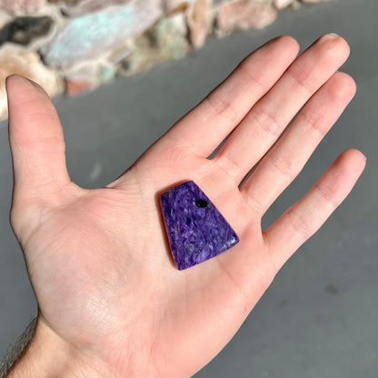 A loose, trapezoid cabochon cut purple charoite stone from Russia.