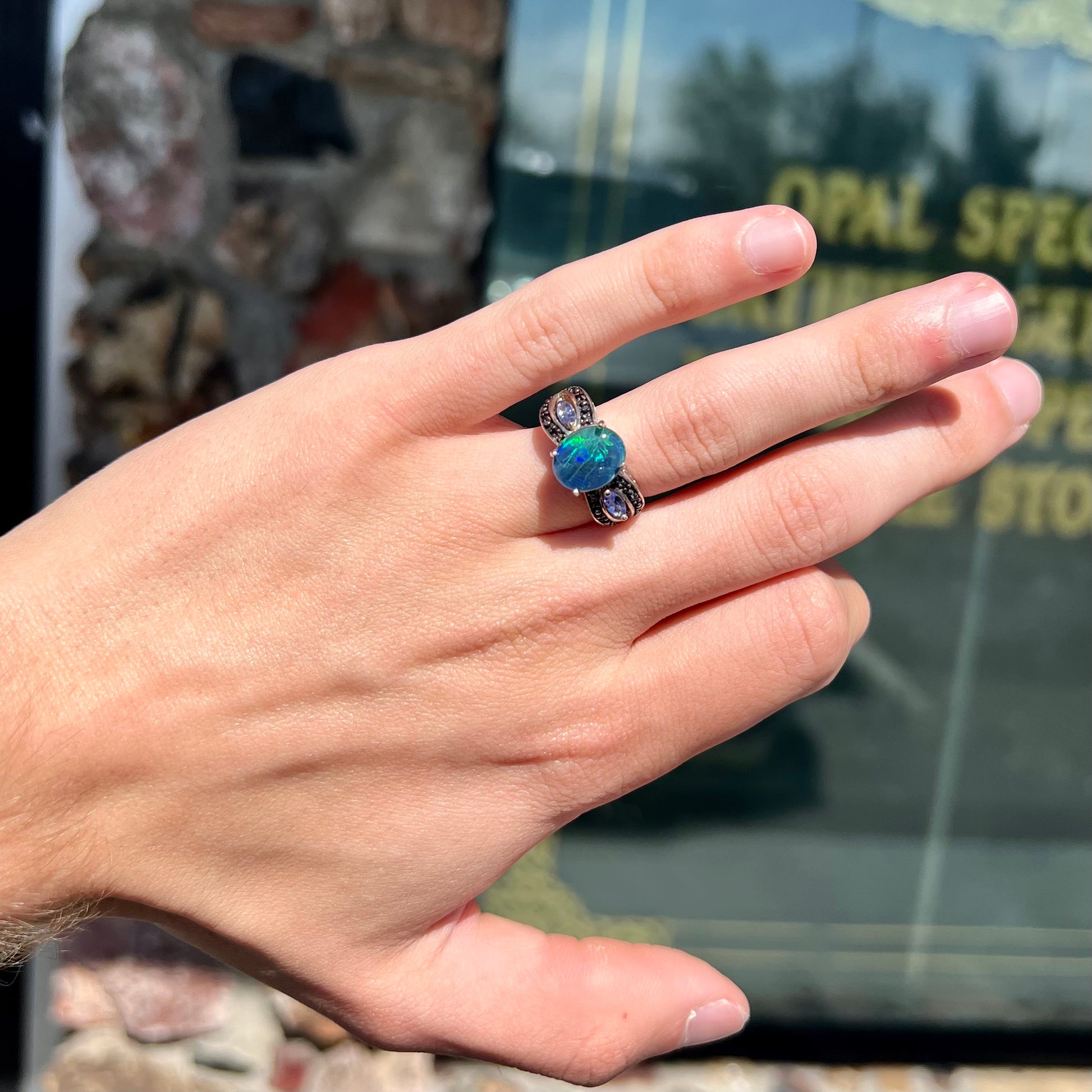 A sterling silver ring set with a black opal triplet, two marquise cut tanzanites, and round black spinel accent stones.