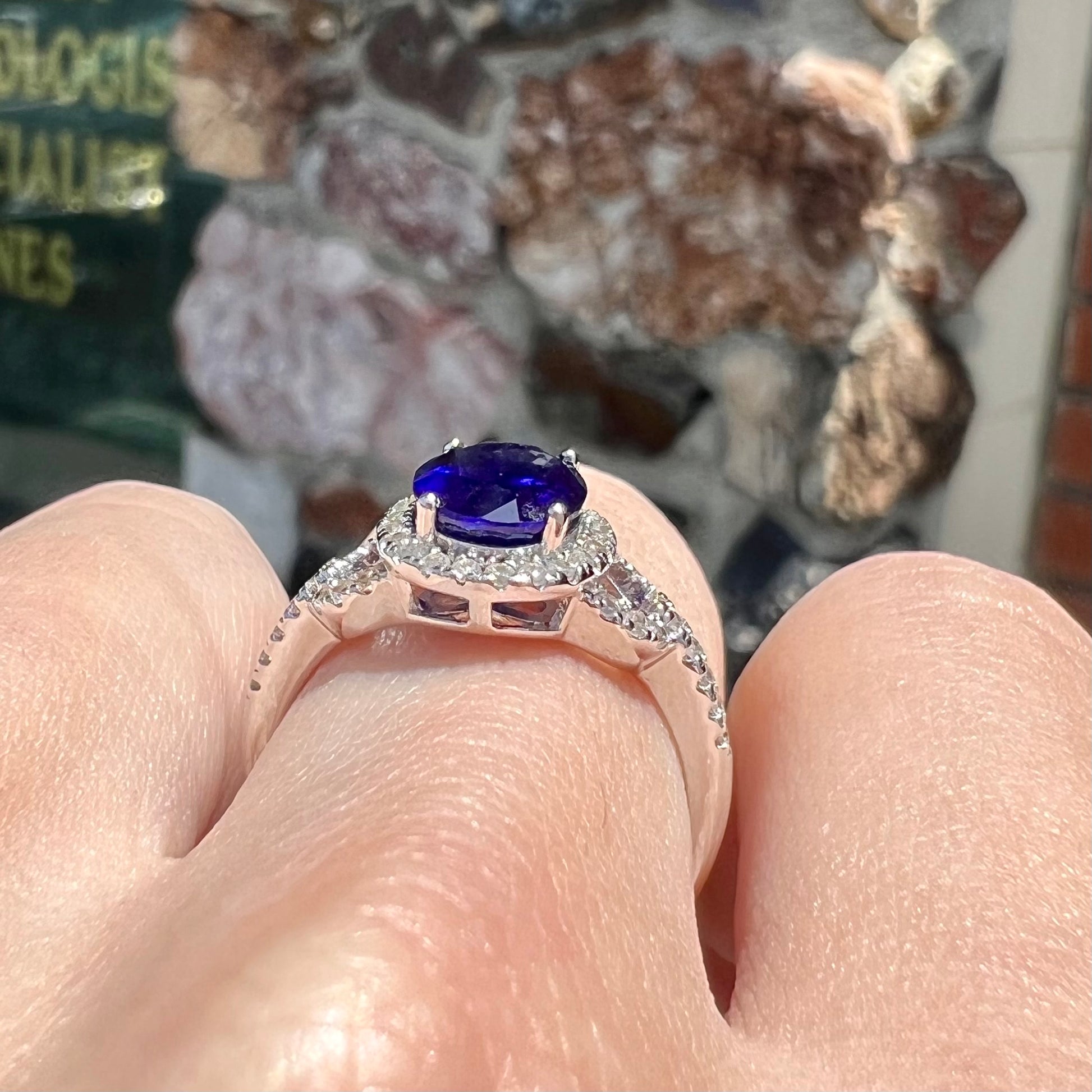 A sterling silver, white zircon halo ring set with an oval cut blue sapphire.