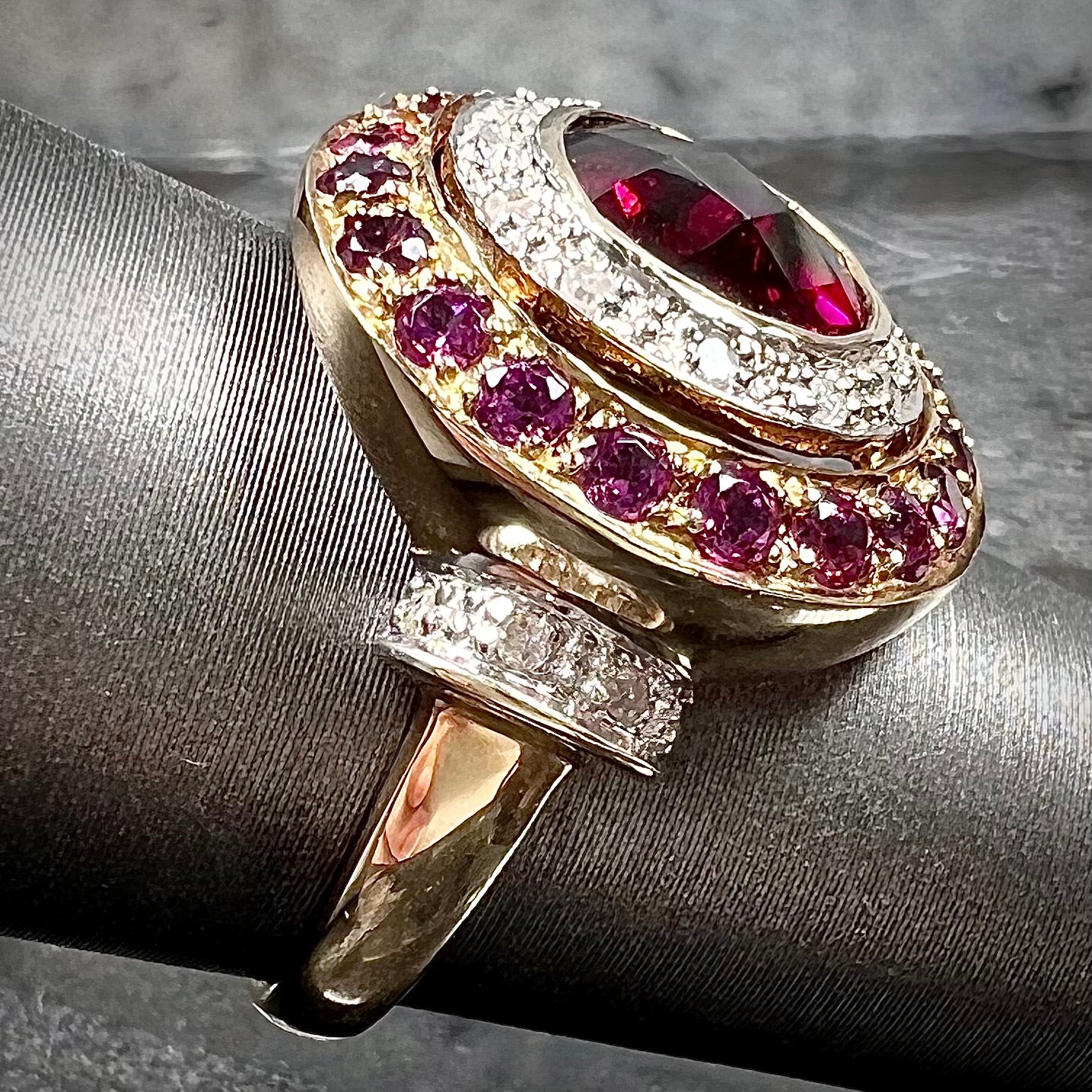 A yellow gold garnet and diamond halo ring set with a checkerboard cut rhodolite garnet center stone.