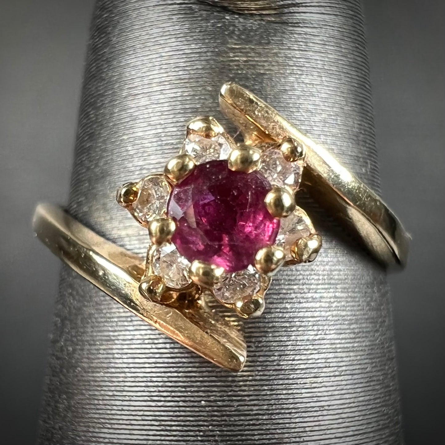 Custom twisted shank ruby and diamond halo yellow gold ring.