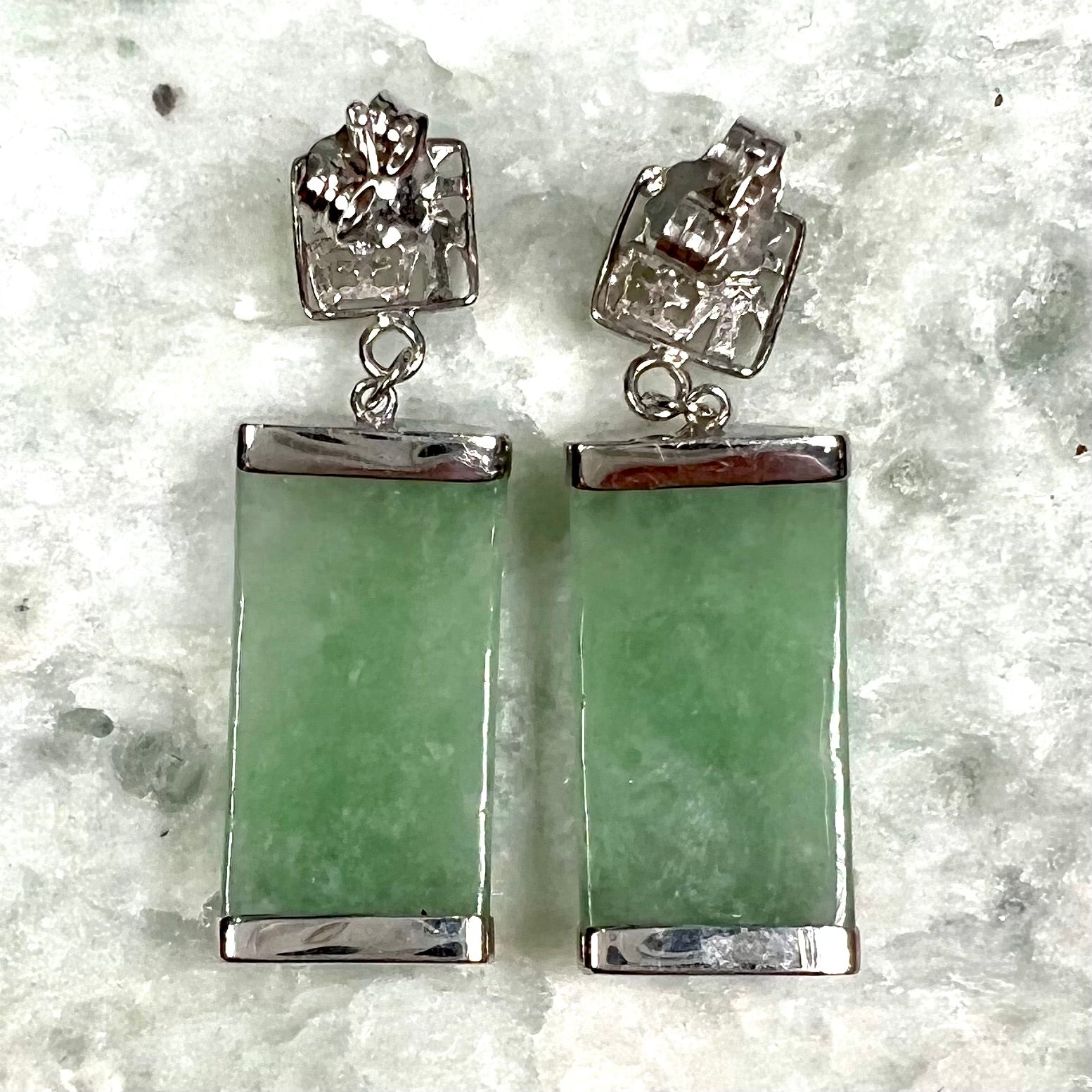 A pair of white gold jadeite dangle earrings with Chinese characters.