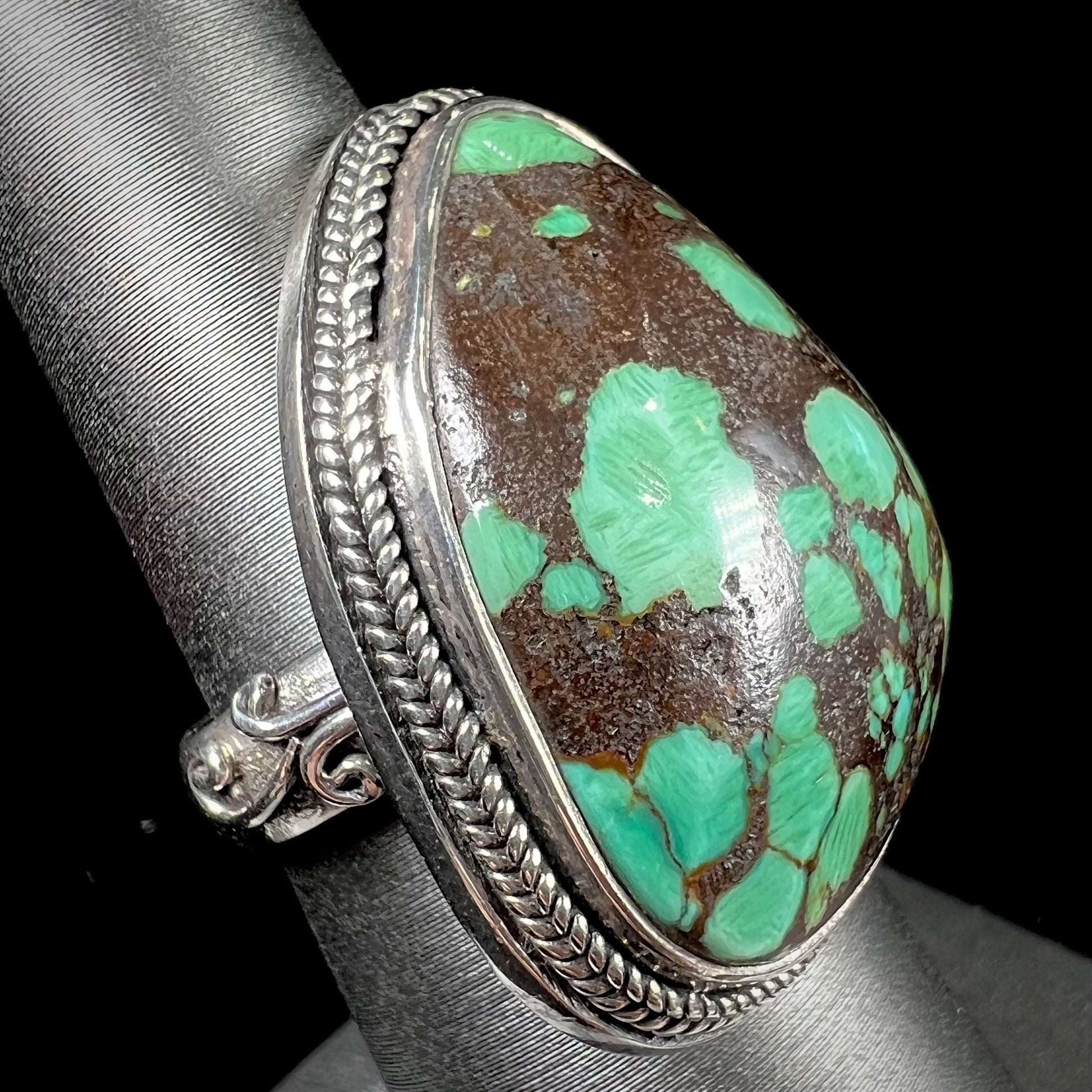 A sterling silver ring bezel set with a green spotted turquoise stone from Carico Lake, Nevada.