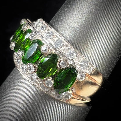 A ladies' two-tone white and yellow gold ring set withseven oval cut chrome diopside stones and cubic zirconia accents.