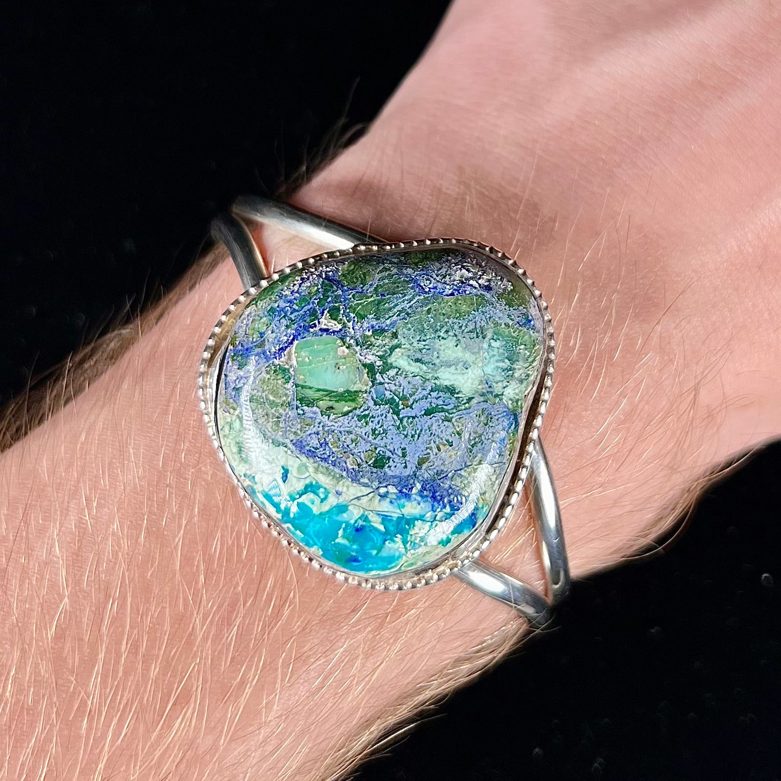 A handmade sterling silver cuff bracelet set with a single stone formed from variscite, chrysocolla, and azurite.