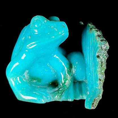 A stone frog peeking from behind a leaf carved from gem silica grade chrysocolla by artist, Ron Stevens.