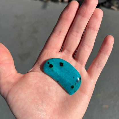 A loose, polished, spotted blue chrysocolla stone.