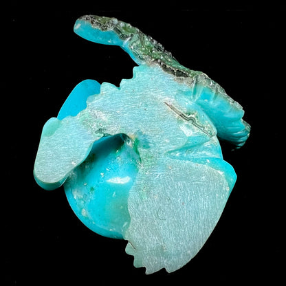 A stone frog peeking from behind a leaf carved from gem silica grade chrysocolla by artist, Ron Stevens.