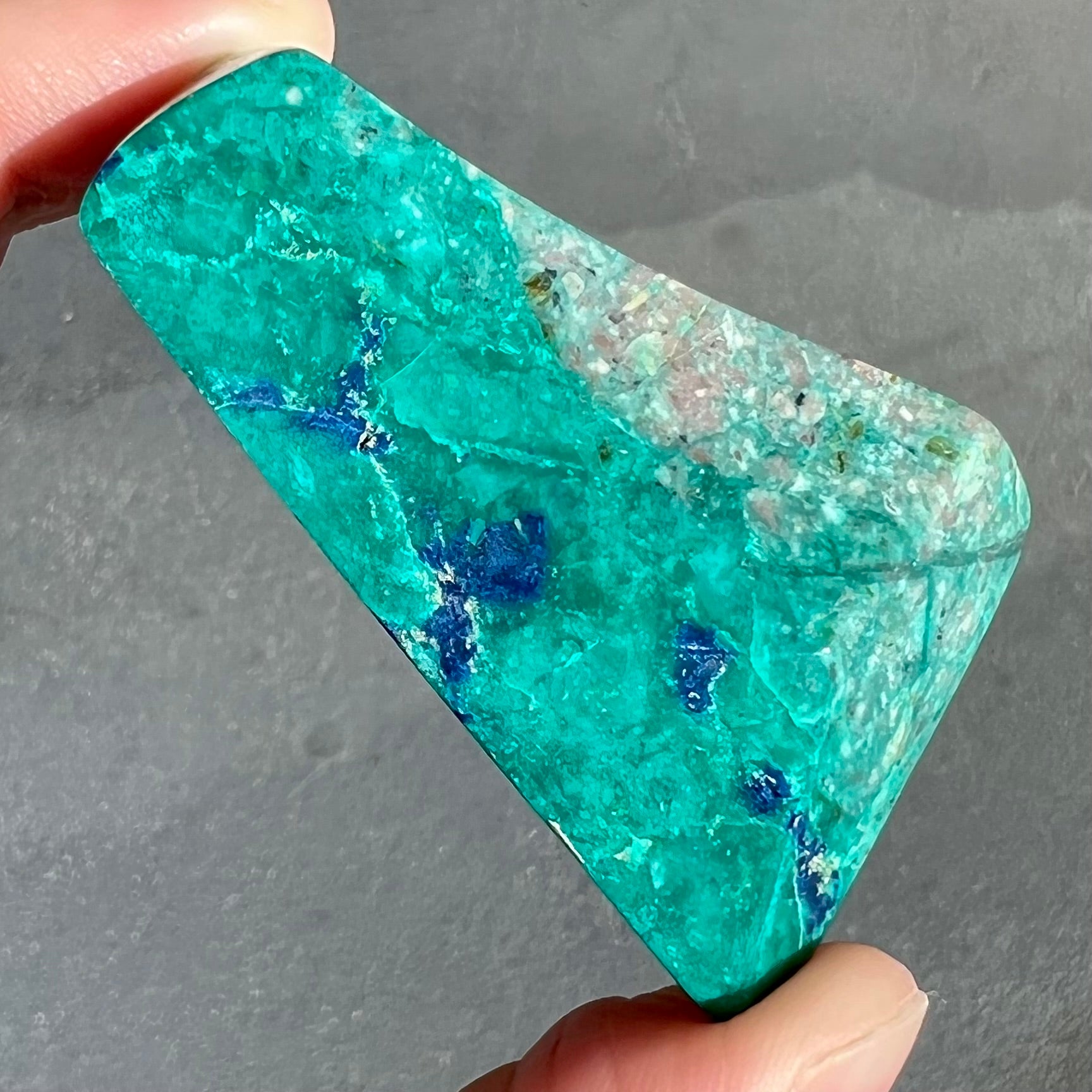 A loose polished sculpture of green chrysocolla with blue azurite inclusions.