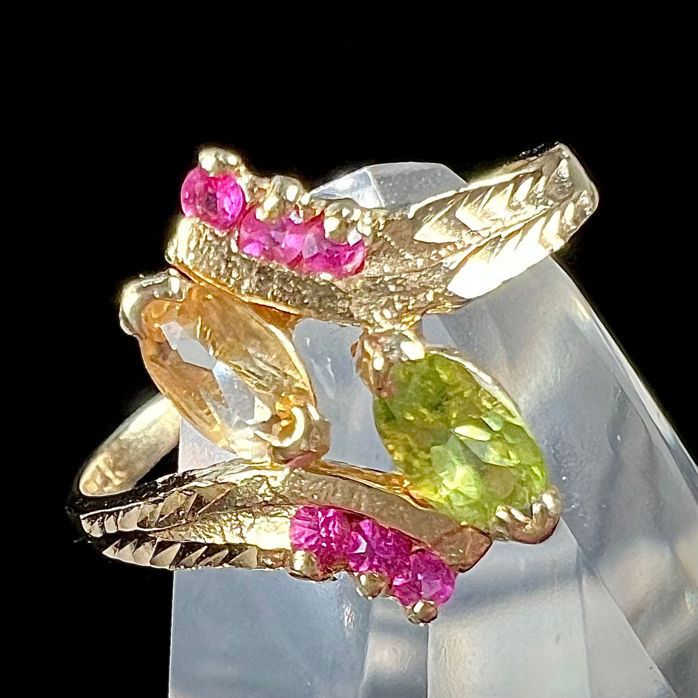 A gold twisted shank ring set with a marquise cut citrine, marquise cut peridot, and round cut ruby accents.
