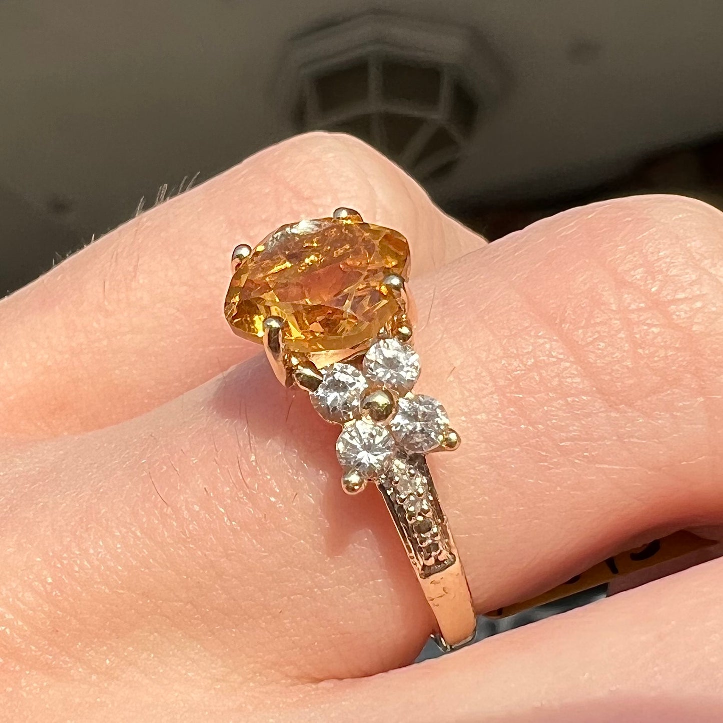 A cushion cut citrine set in a yellow gold ring with four round white sapphires and two diamonds on each side.