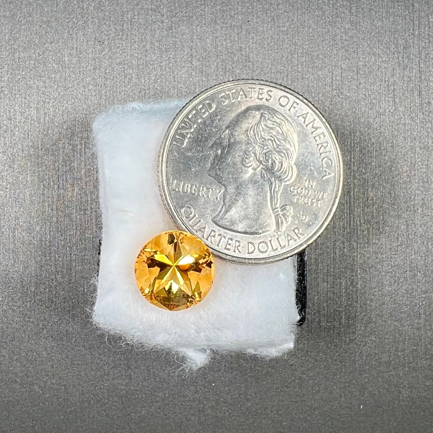 A loose, faceted round cut citrine stone with back facets that form a five pointed star.