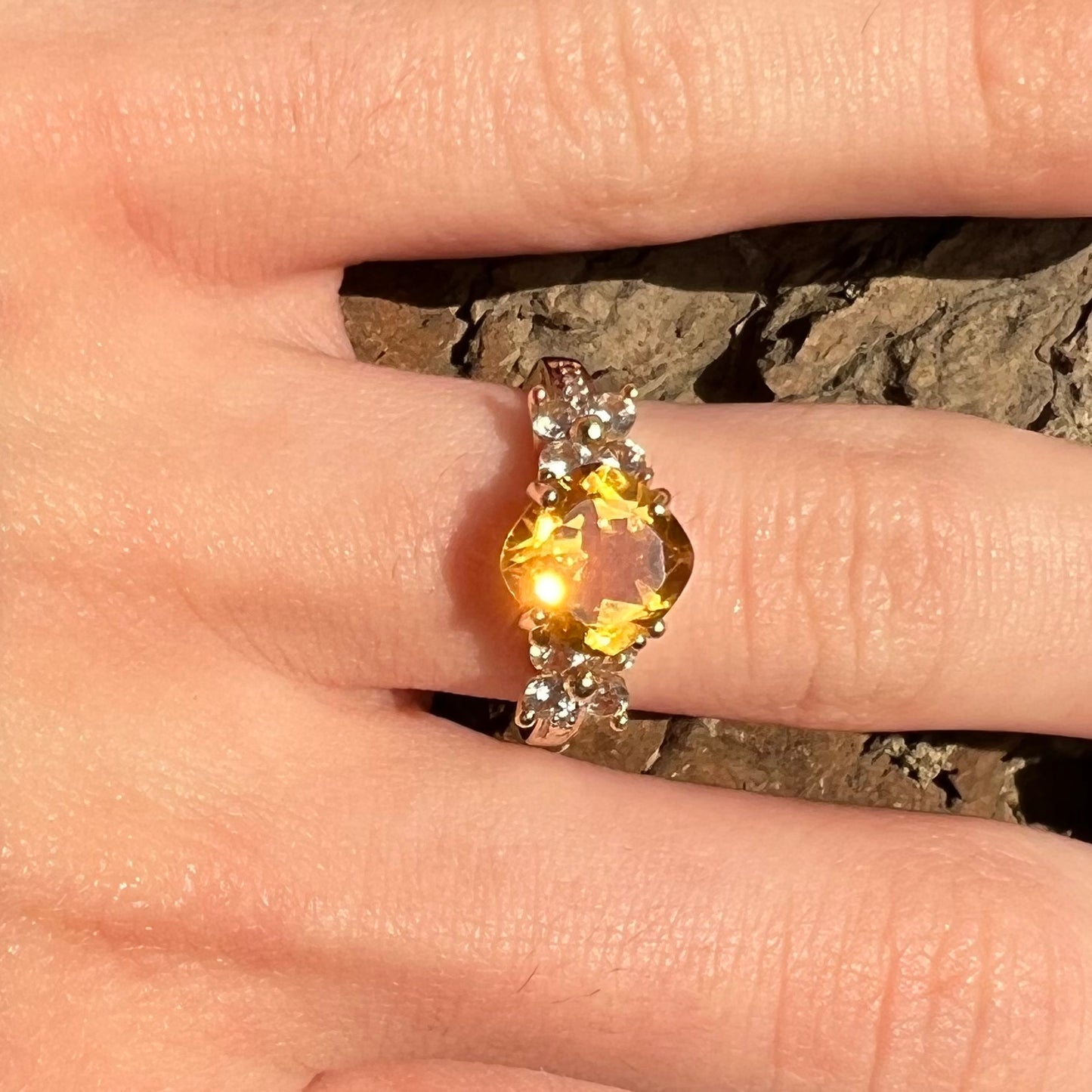 A cushion cut citrine set in a yellow gold ring with four round white sapphires and two diamonds on each side.