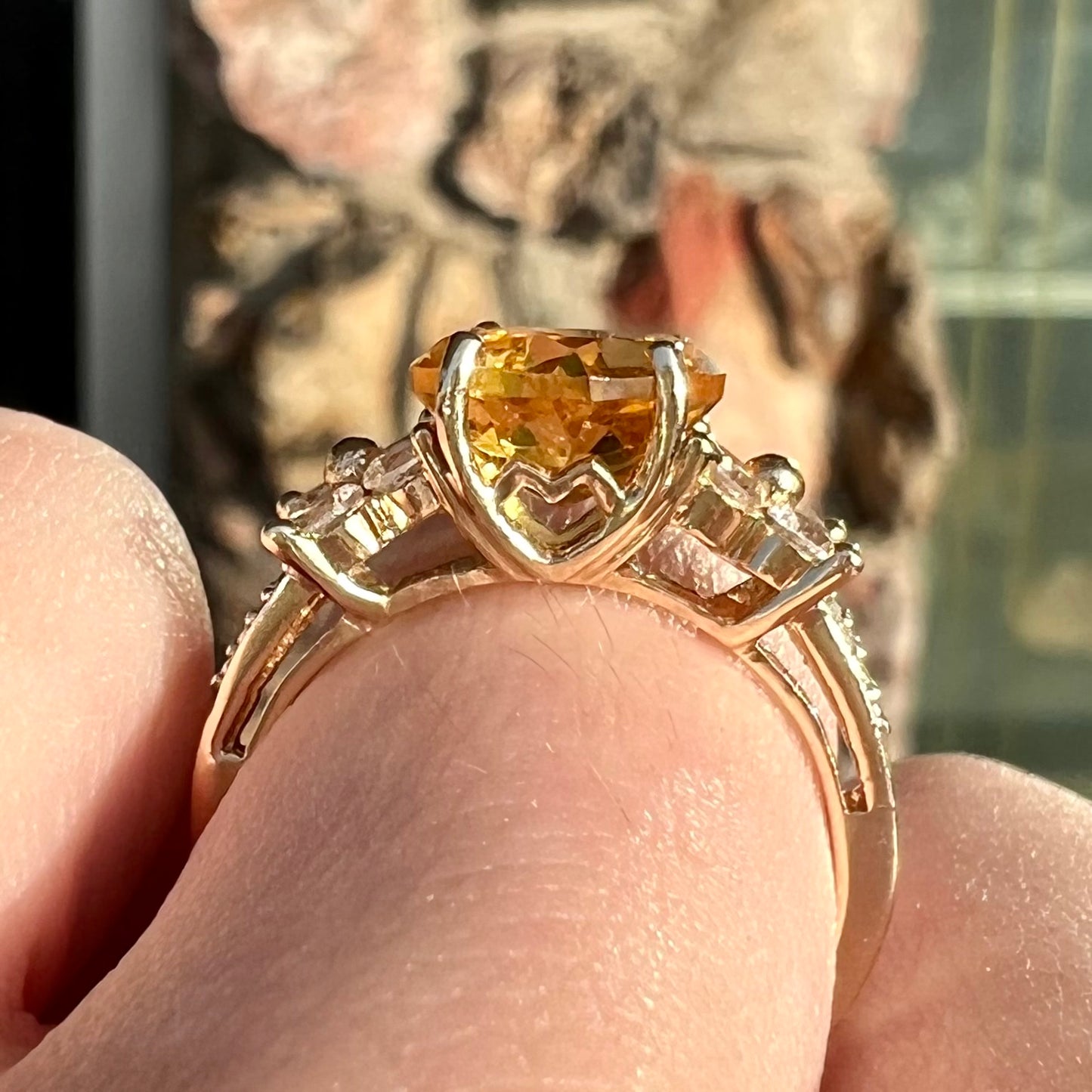 A cushion cut citrine set in a yellow gold ring with four round white sapphires and two diamonds on each side.