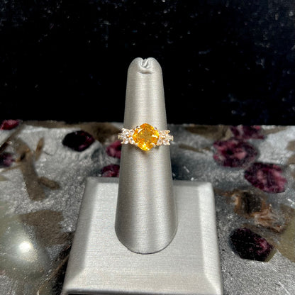 A cushion cut citrine set in a yellow gold ring with four round white sapphires and two diamonds on each side.