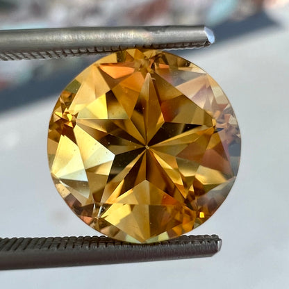 A loose, faceted round cut citrine stone with back facets that form a five pointed star.