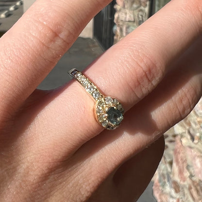 Yellow gold alexandrite and pave set diamond ladies' ring on a hand in natural sunlight.