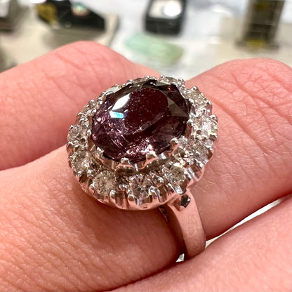 A white gold diamond halo ring set with a purplish faceted oval cut color change garnet.