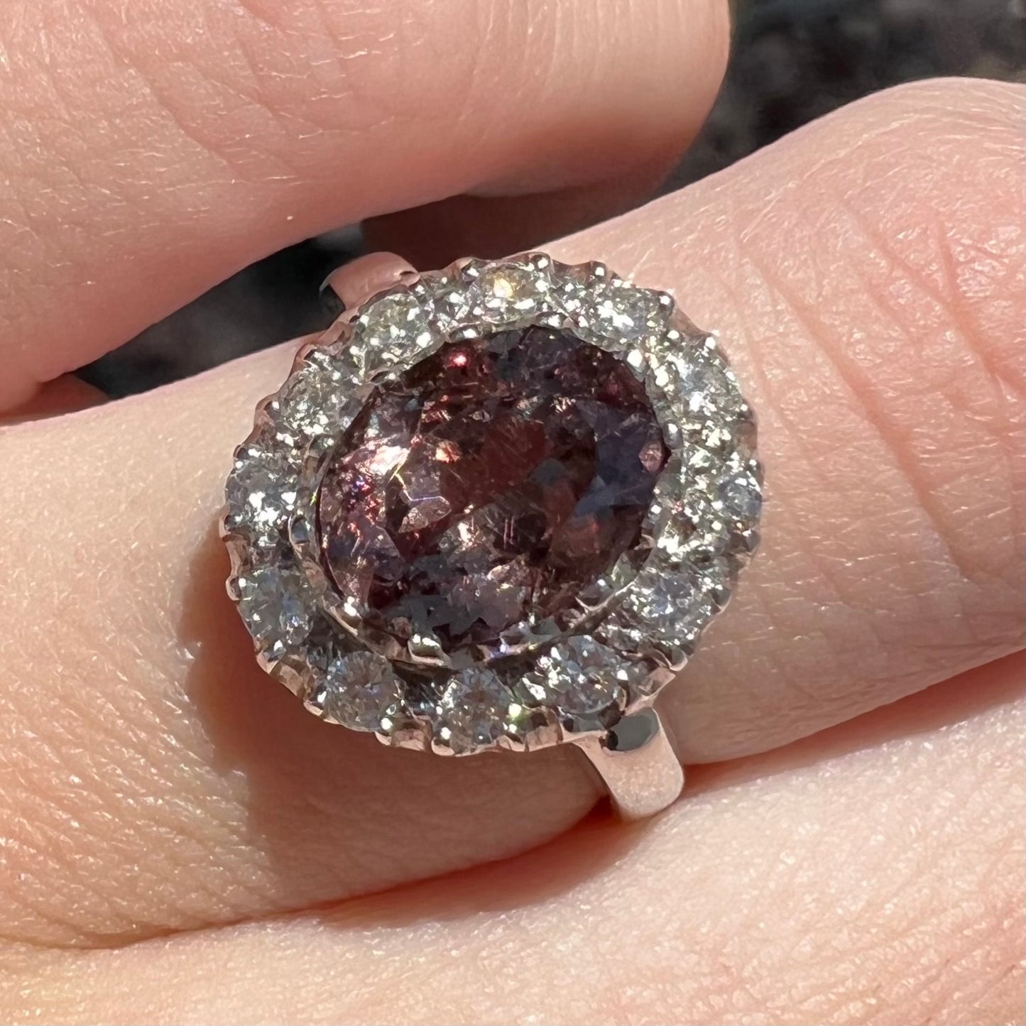 A white gold diamond halo ring set with a purplish faceted oval cut color change garnet.