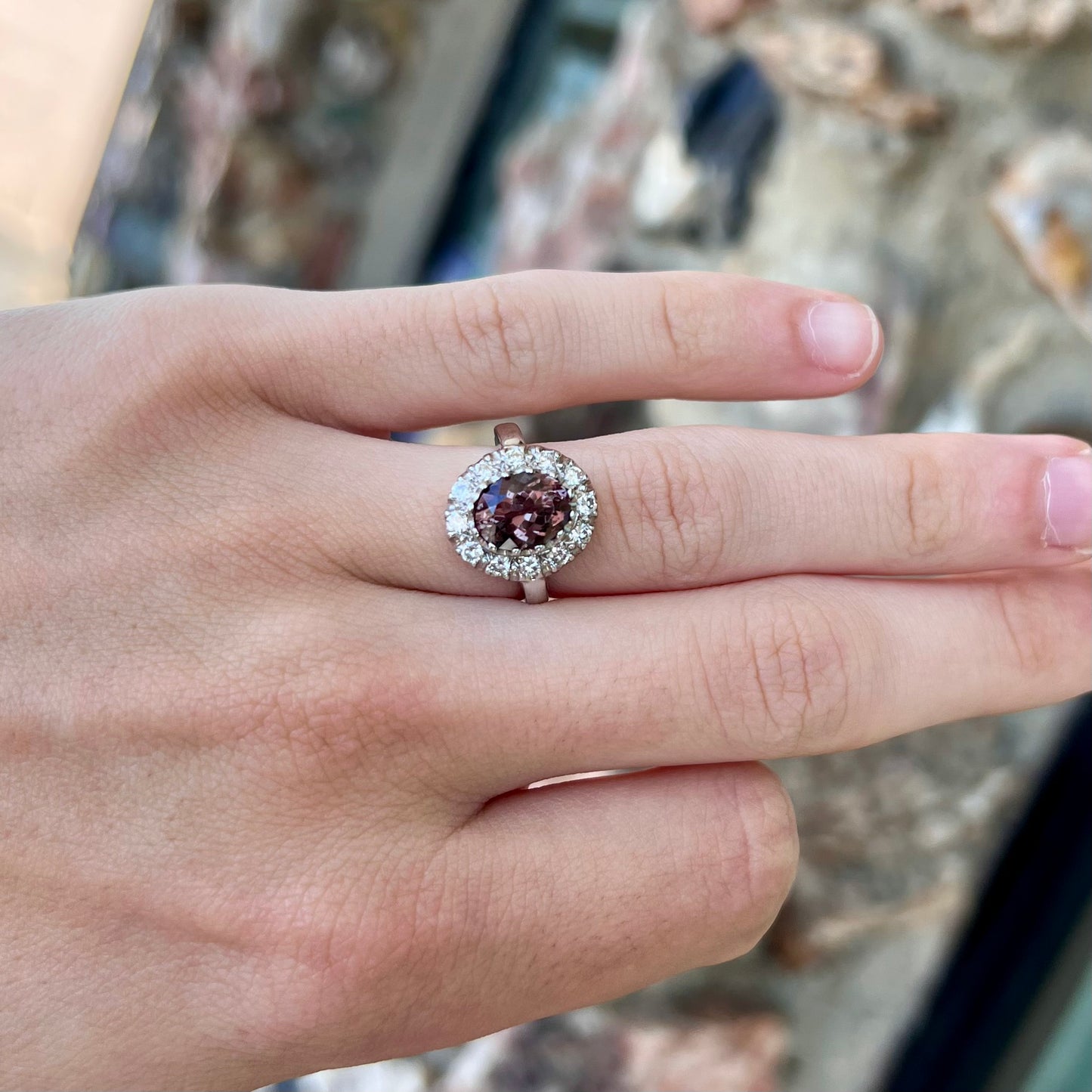 A white gold diamond halo ring set with a purplish faceted oval cut color change garnet.