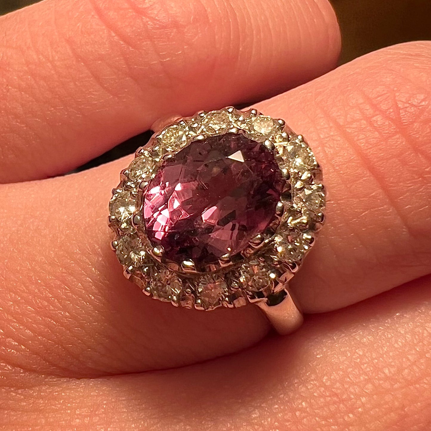 A white gold diamond halo ring set with a purplish faceted oval cut color change garnet.