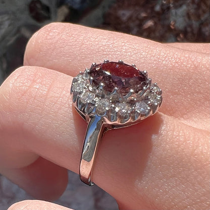 A white gold diamond halo ring set with a purplish faceted oval cut color change garnet.