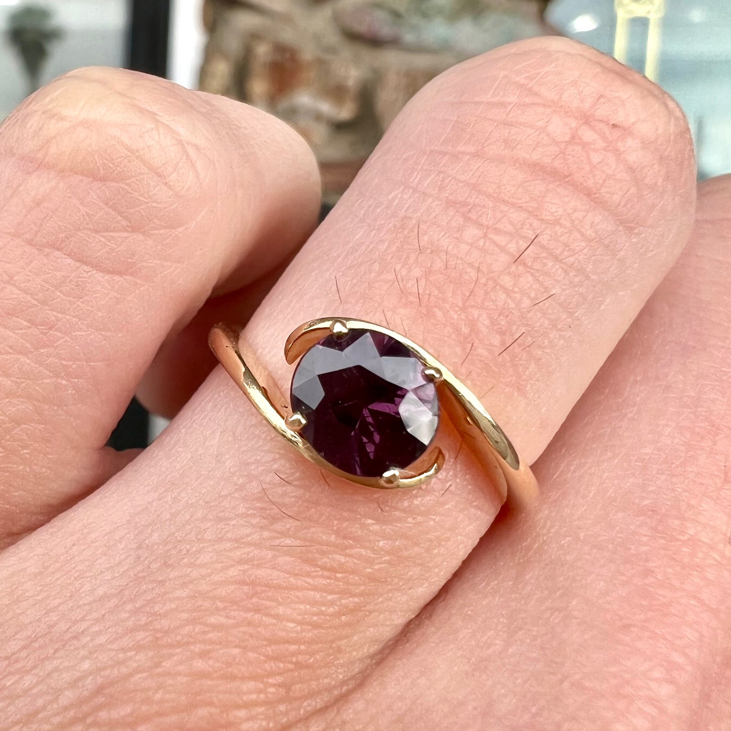 A yellow gold solitaire engagement ring set with a faceted oval cut color change garnet stone.