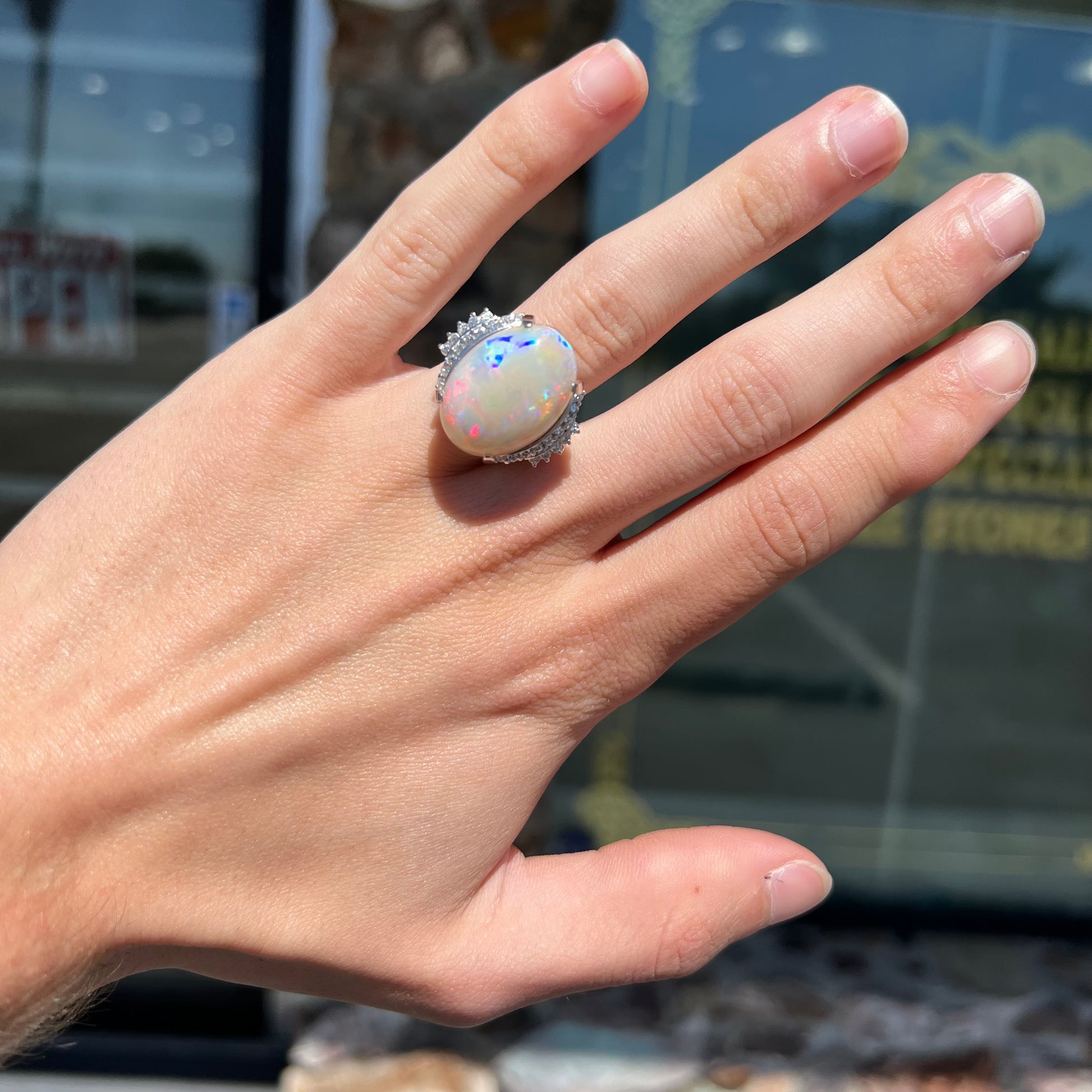 An oval cabochon cut Coober Pedy, Australian opal prong set in a platinum ring with round cut diamonds.