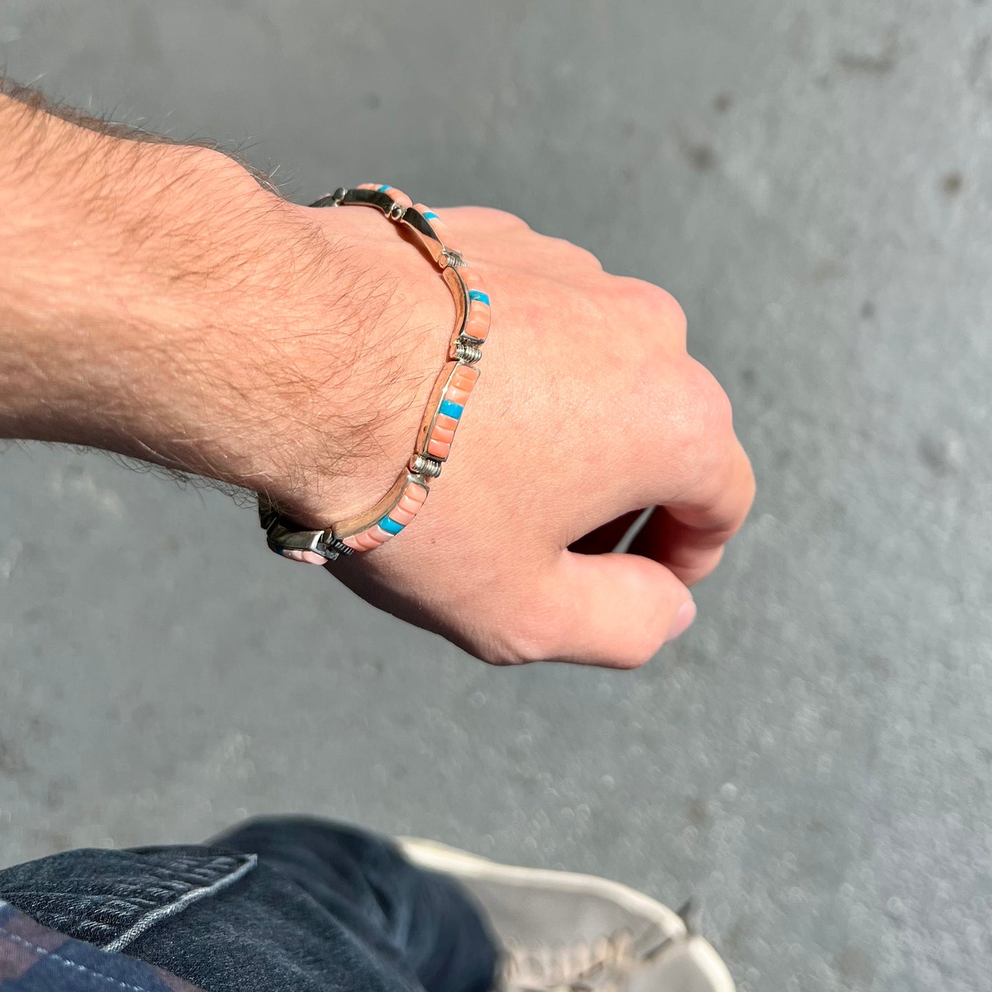 A ladies' sterling silver tennis style bracelet set with polished pink coral and turquoise inlay.