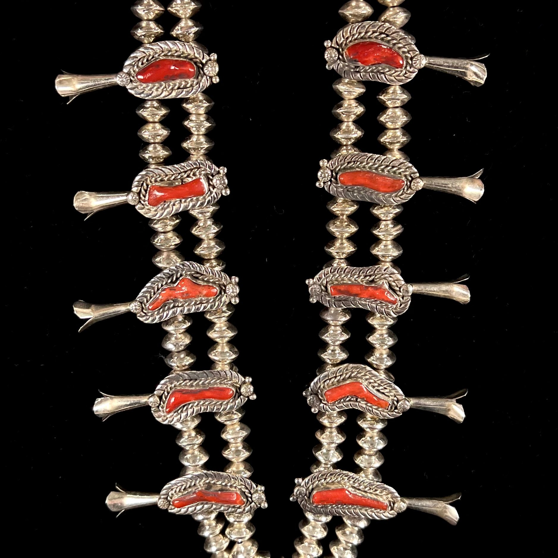 A Navajo style squash blossom necklace set with red coral branches, handmade by artist Delbert Chatter.