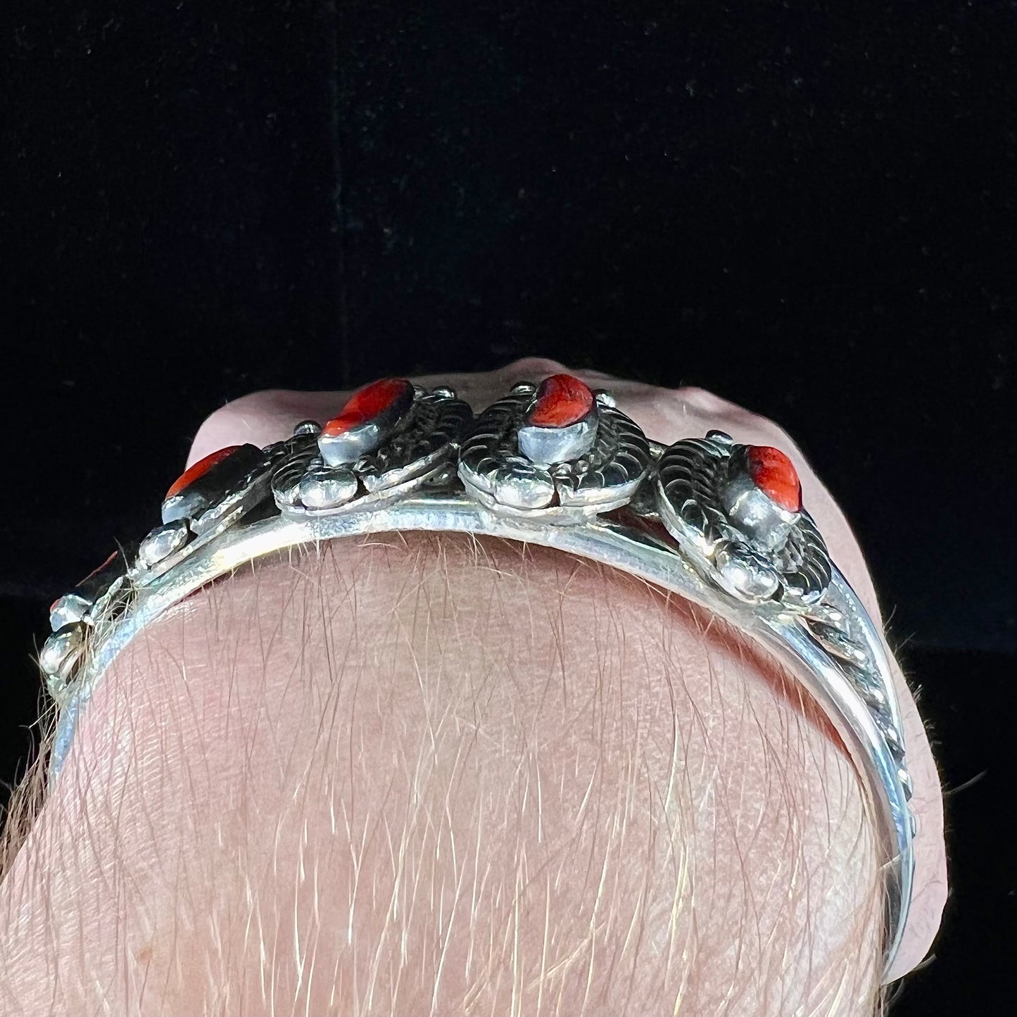 A sterling silver cuff bracelet set with polished coral branches handmade by Navajo artist, Delbert Chatter.