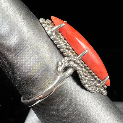 A prong-set silver ring set with a red marquise cut coral.