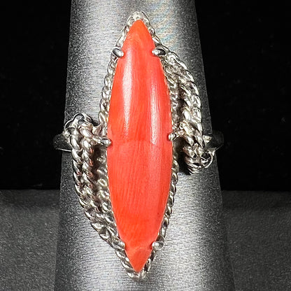 A prong-set silver ring set with a red marquise cut coral.