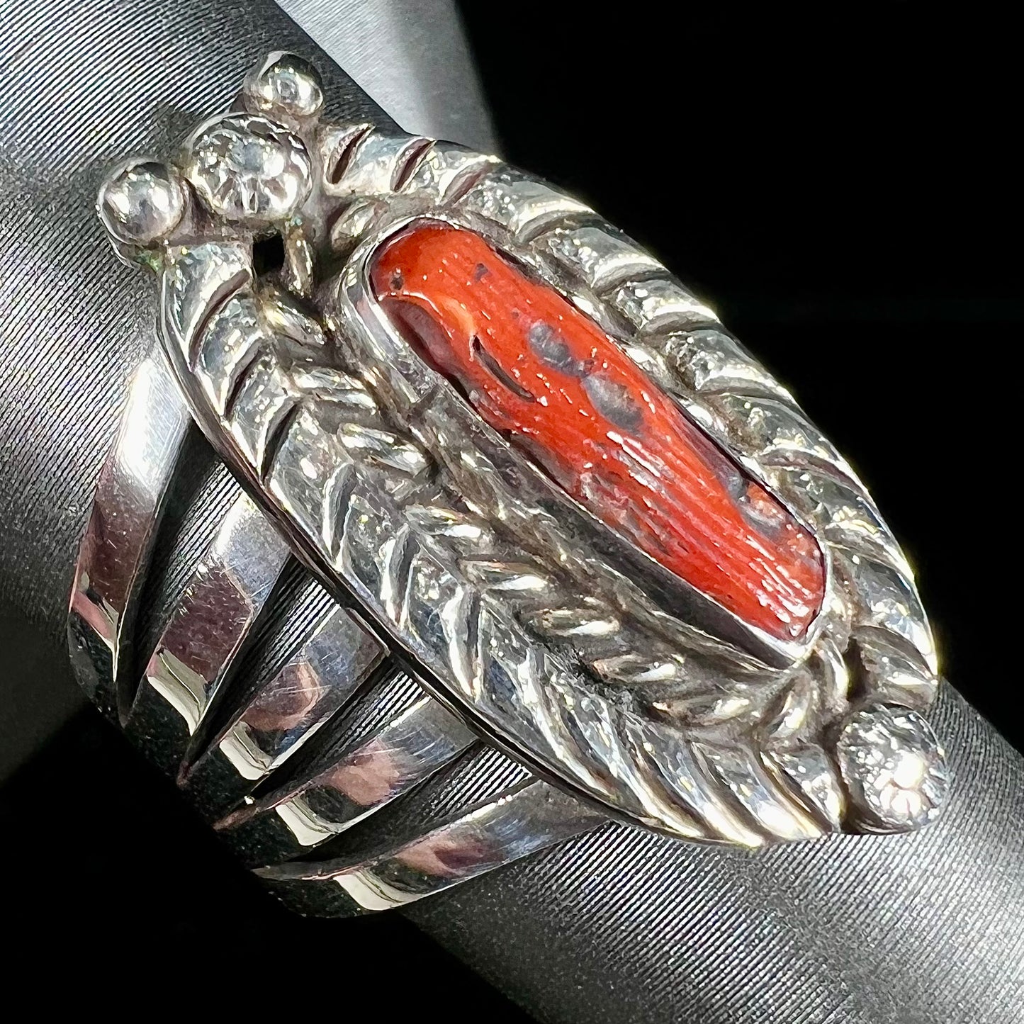 A sterling silver ring set with a polished red coral branch handmade by Navajo artist, Delbert Chatter.