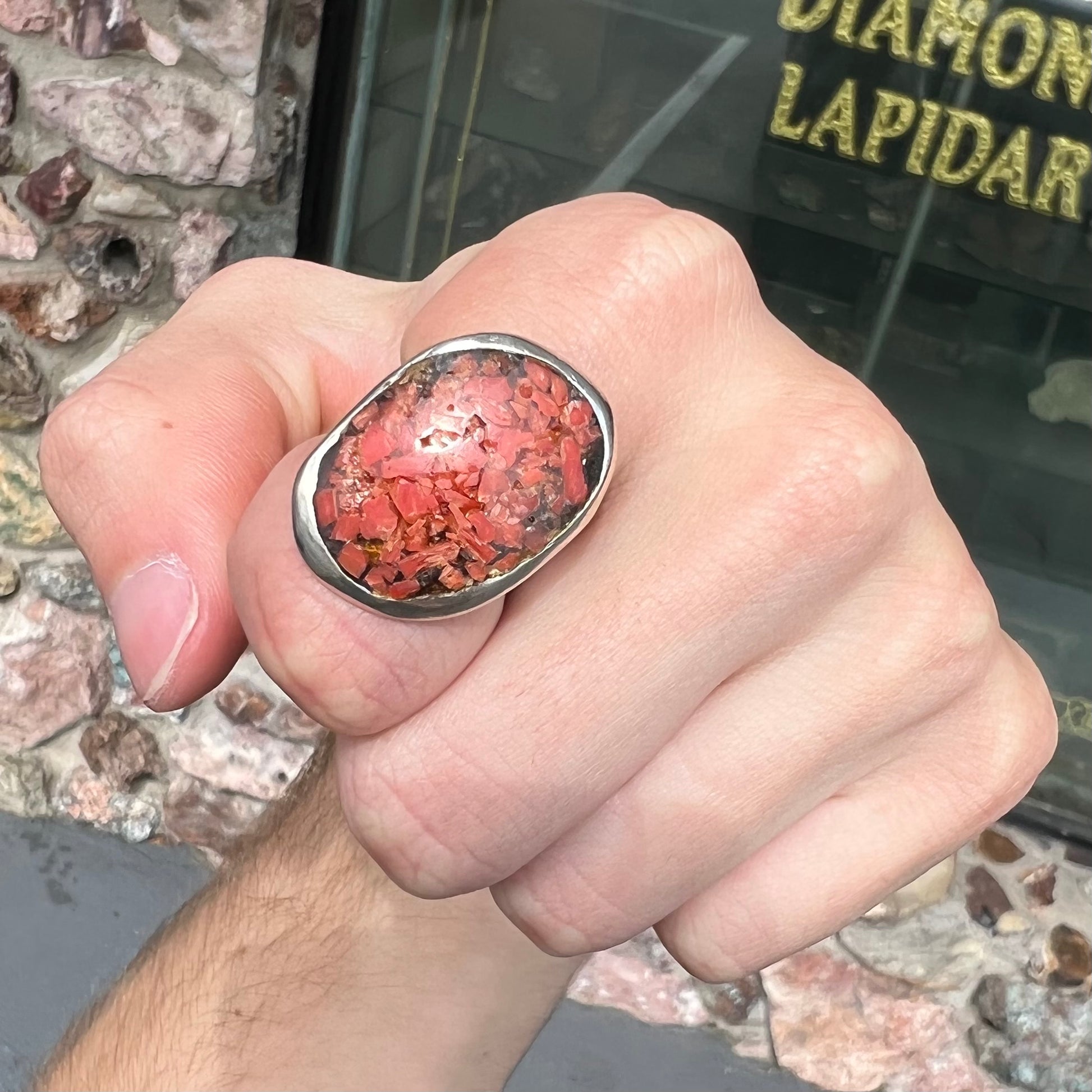 A rustic style, handmade silver men's ring set with crushed red coral.