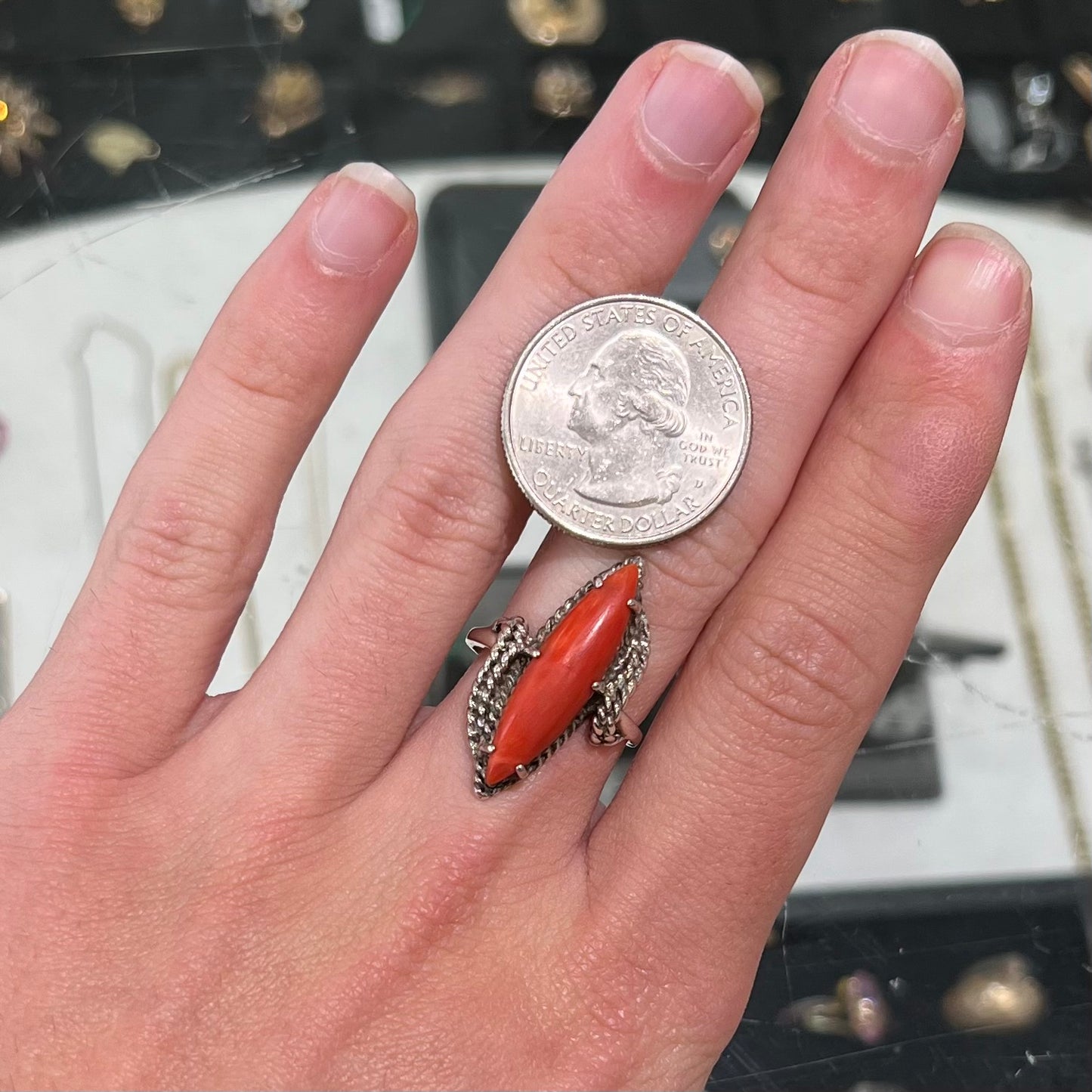 A prong-set silver ring set with a red marquise cut coral.
